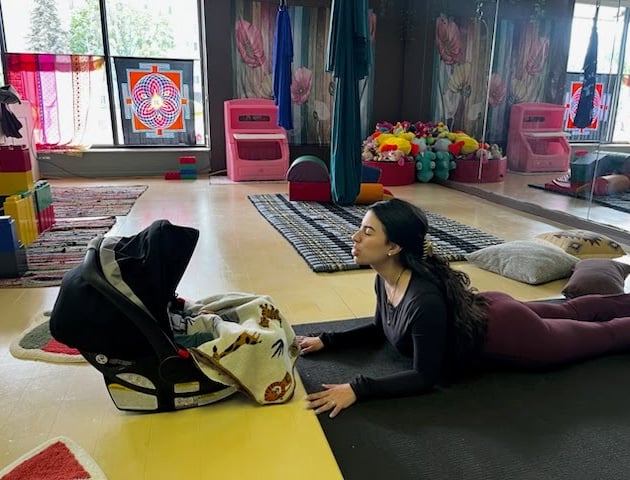 Mother in Sphinx Pose with infant in a car seat in front of her