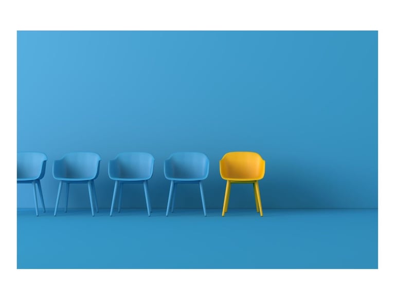 A blue wall and floor, with four blue chairs and one yellow chair illustrating interviews
