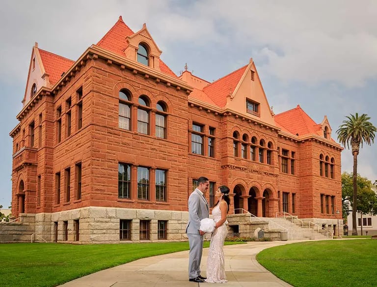 A bride and groom standing in front of the Old Orange County Courthouse