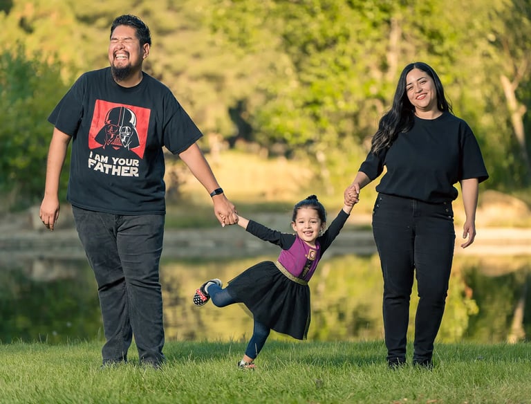 family photoshoot of a man and woman holding hands and holding kid by her hands