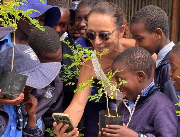 Young school children holding trees surrounding a teacher 