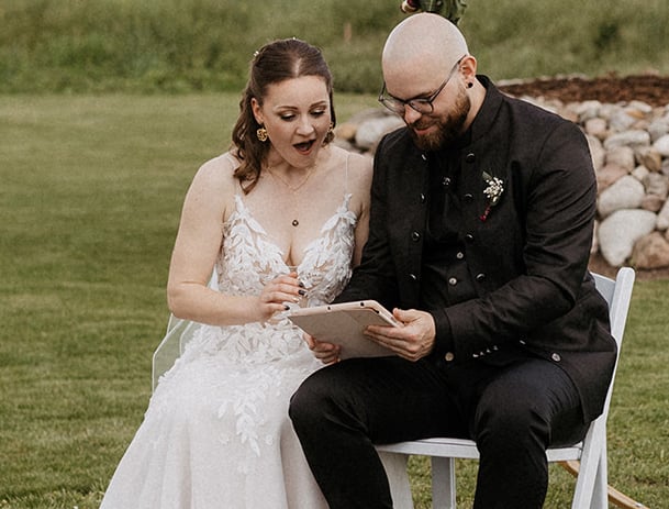 das Hochzeitspaar wird mit einem Video ihrer Lieblingsband überrascht. die beiden blicken erstaunt auf das iPad