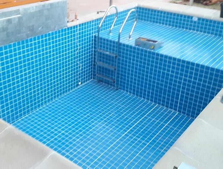 a pool with a blue tiled pool and a wooden deck