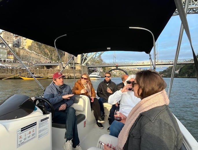 Guests chatting with Captain Francisco on Endure, with Porto’s Dom Luís I Bridge in the background