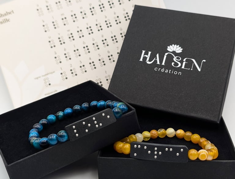 Bracelets perles avec plaques en braille, dans un écrin noire accompagné d'un alphabet braille.