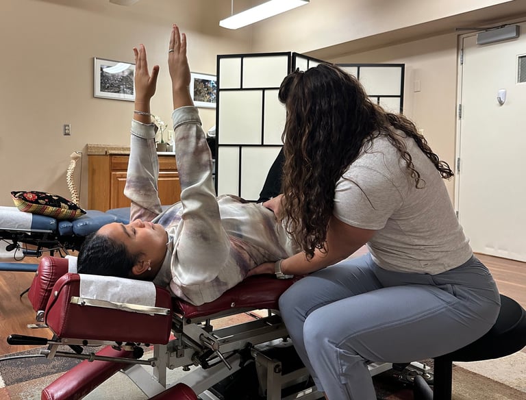 Chiropractor with hands on patients stomach and lower back, coaching form for rehab exercise.