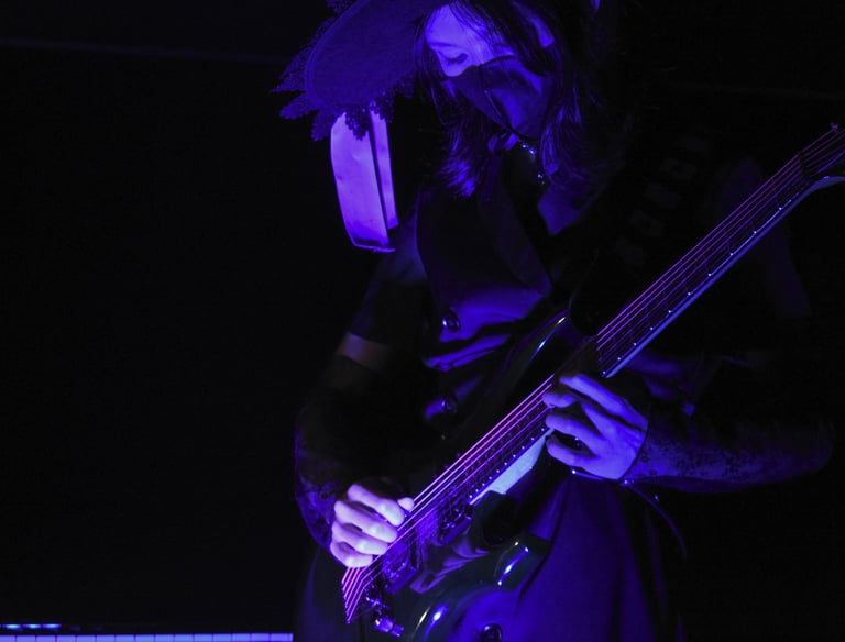Guitar player in dark atmosphere lit with purple lighting