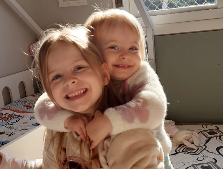 two young children in a bed with a teddy bear