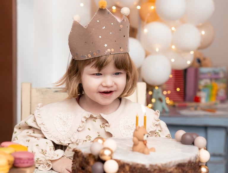 mala djevojčica sjedi za stolom i puše svijeće na torti