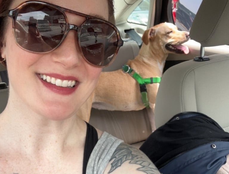 a woman with tattoos on her arm and a dog in the car