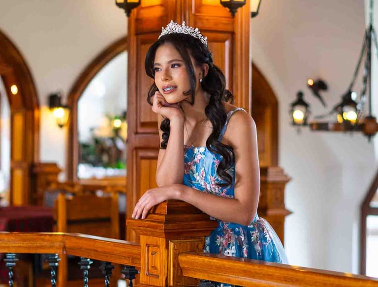 Retrato de quinceañera con vestido azul con detalles florales , una tiara, en un espacio de madera, luz cálida Quito Ecuador