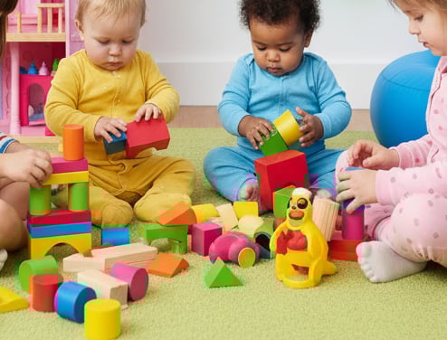Bebês brincando em uma sala de educação infantil colorida