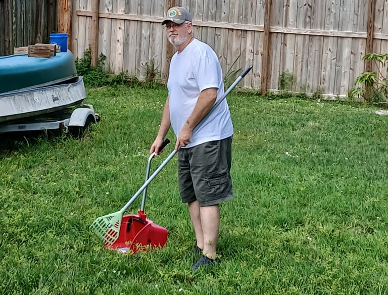 Robert using a sanitized scooper to remove waste from a customers back yard