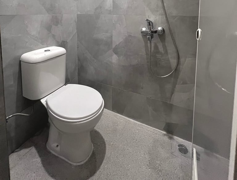 Kamar mandi dalam kos dengan shower, toilet duduk, dan water heater di Kos Si Bos Surabaya