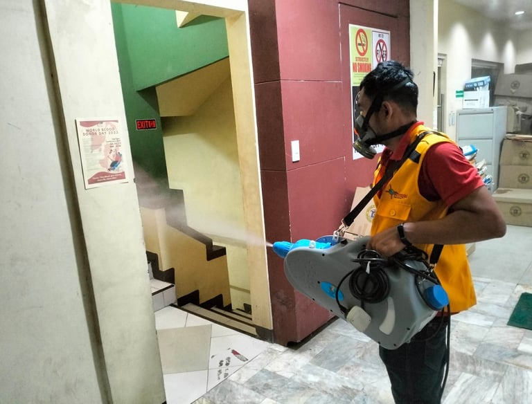 Professional pest control technician spraying disinfectant mist in an office building hallway.