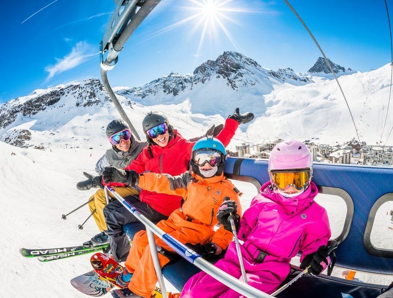 A happy family riding a ski lift at a mountain resort on a sunny winter day.
