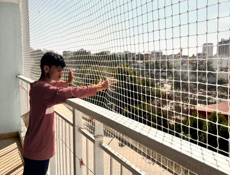 Technician from Sukumari Safety Nets carefully fixing netting around a window frame.