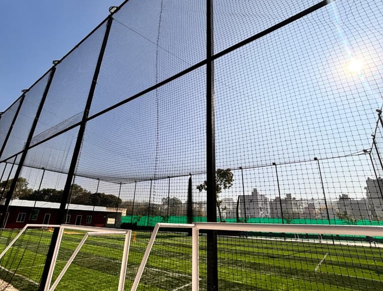 Wide shot of a sports ground fully enclosed with safety nets on a sunny day.