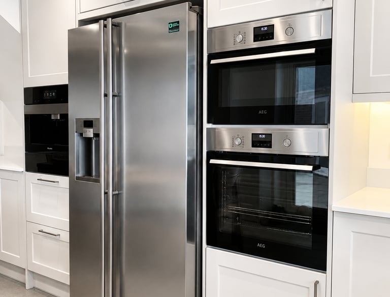 Stainless steel American-style fridge freezer alongside integrated double ovens in Iffley