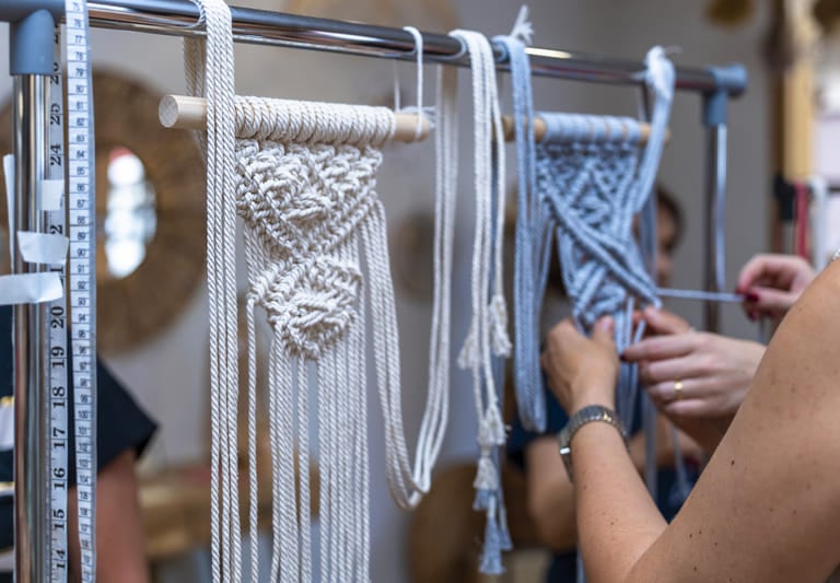 Proyectos de tapices de macramé hechos a mano colgados en un soporte de un taller de arte textil