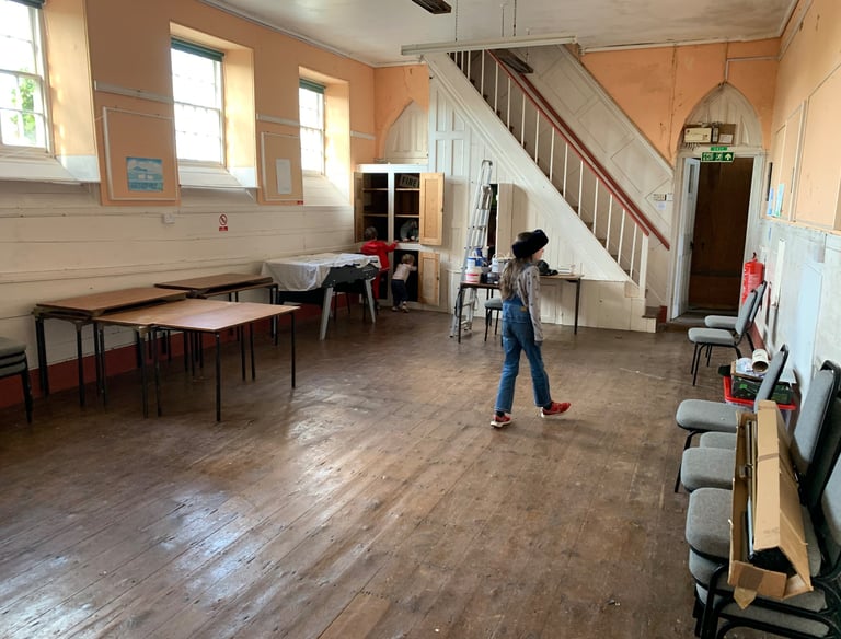 Large open hall mid-renovation with tools and furniture pushed aside.