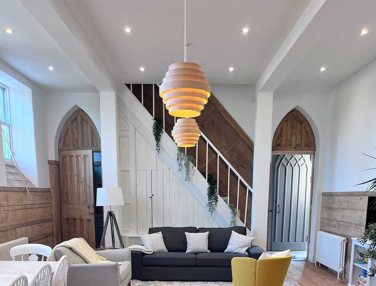 Completed staircase and living space with vaulted ceiling and feature lighting.
