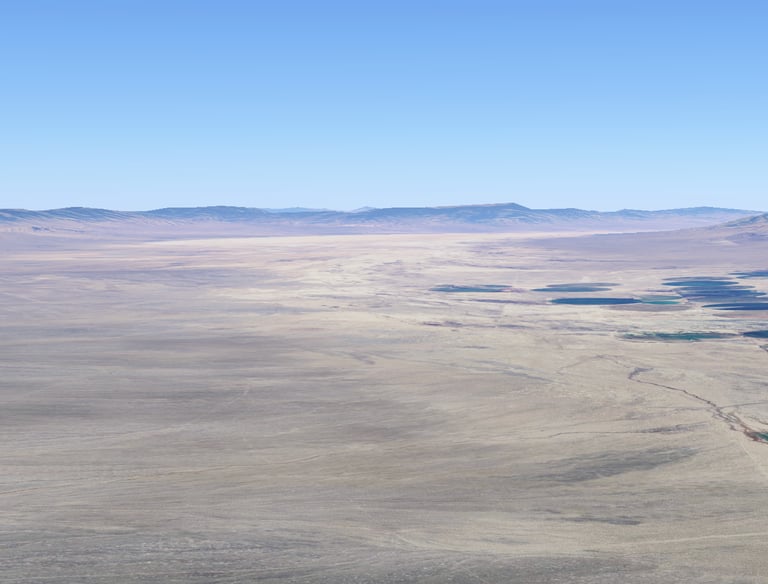 a view of a desert landscape with a lake and mountains in the background