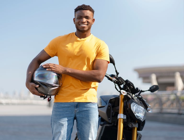 A Motorcyclist is holding a helmet and standing next to his bike on the training track.