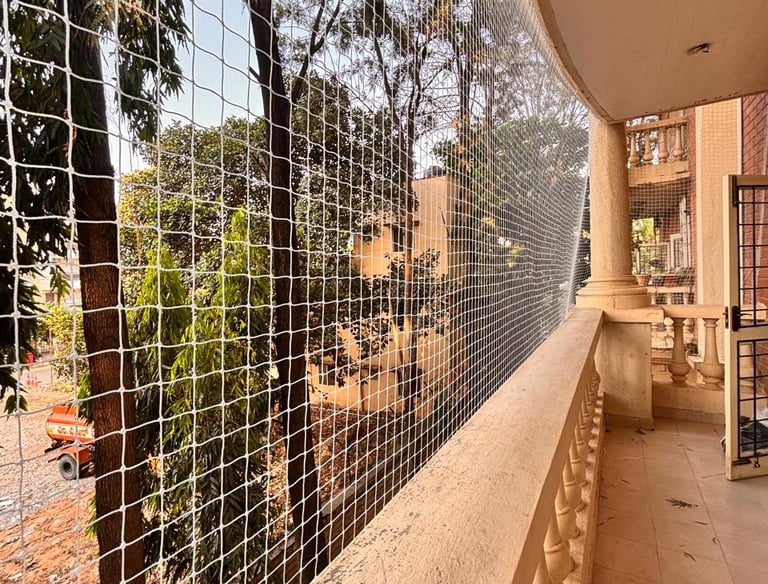 A clean, secure balcony fitted with sturdy pigeon netting under bright daylight.
