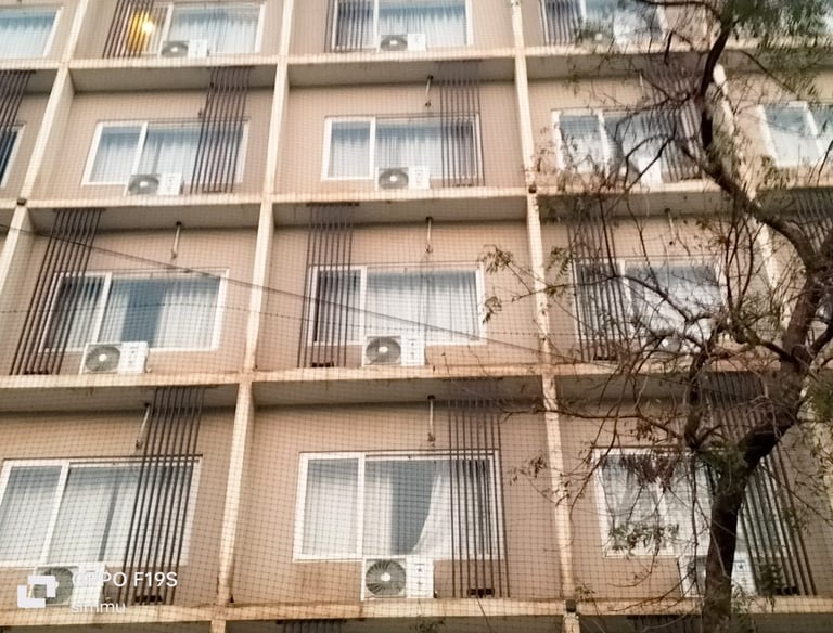 Technician carefully fitting anti-pigeon netting over a Koyambedu market stall.