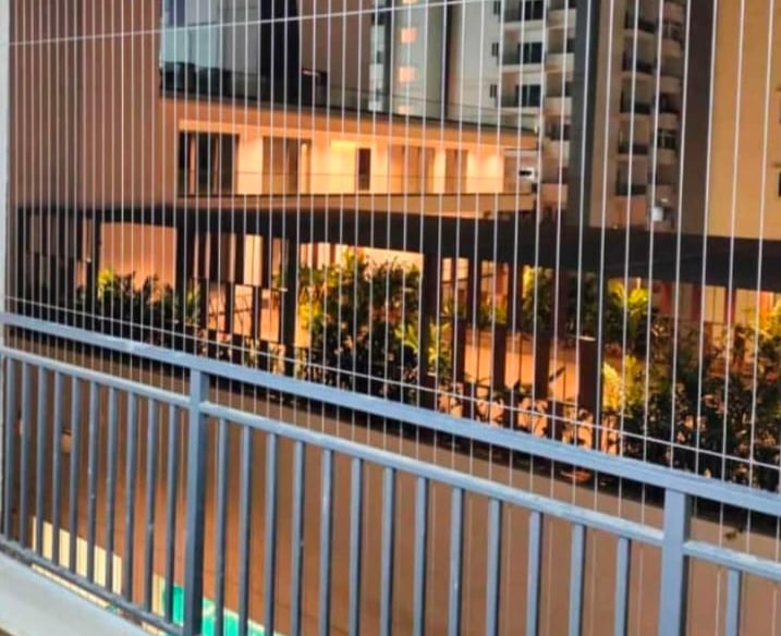Technician from Arjilli Enterprises installing invisible grills on a residential balcony.