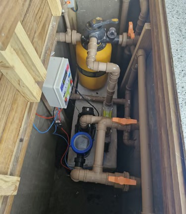 Sistema de filtragem de piscina com filtro de areia amarela, bomba e encanamento de PVC em caixa de