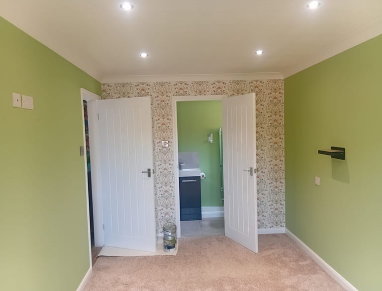 A feature wall with a repeating flower design, and the surrounding walls painted a pale green.