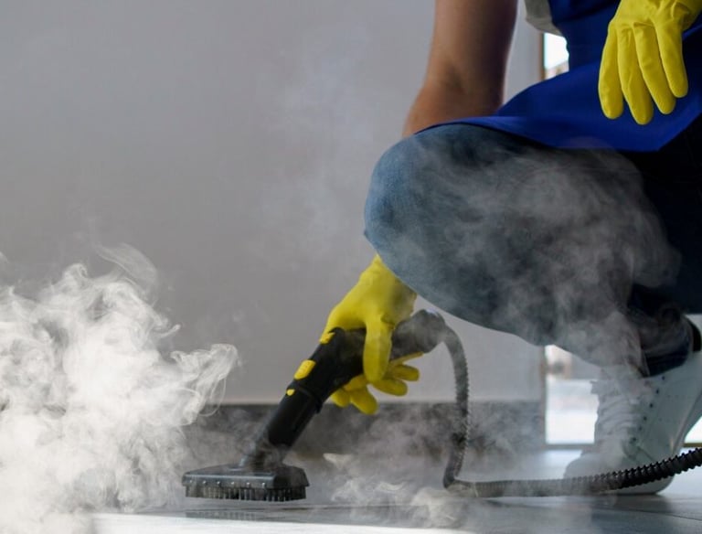a person in a blue shirt and yellow gloves is using a steam cleaner