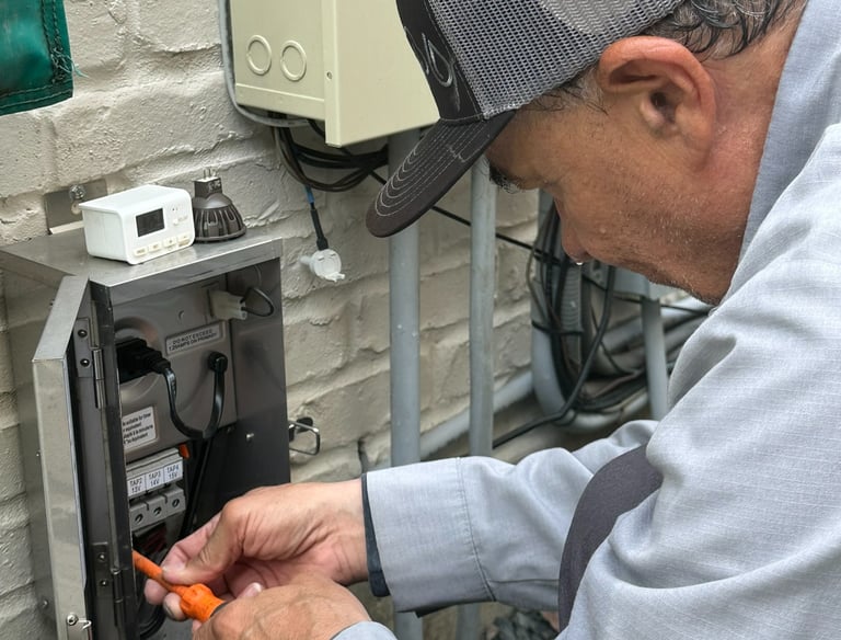 Electrician installing a professional low voltage landscape lighting transformer on an exterior wall.