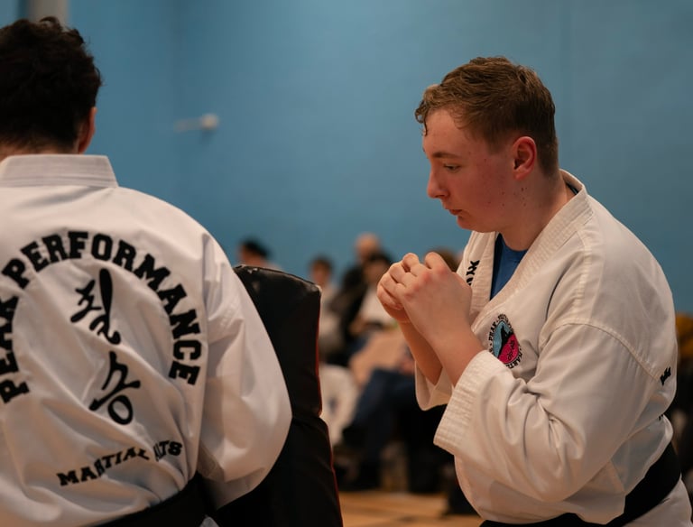 A young martial artist in a white karate gi practices punches with a partner during a training session.