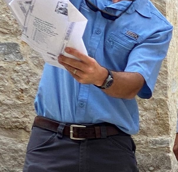 a man in a blue shirt is holding a cell phone designing lights on a house