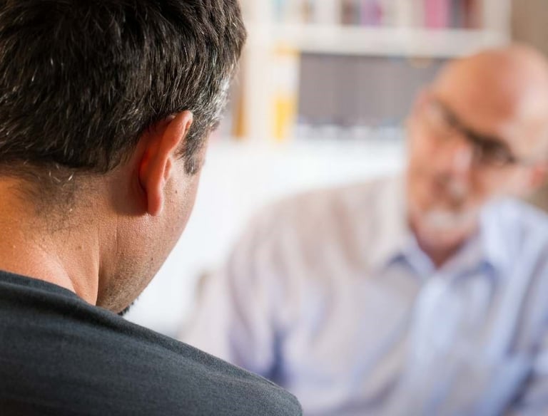 a man in a blue shirt is looking at a cell phone