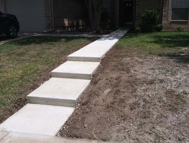 a concrete walkway with steps leading up to a house