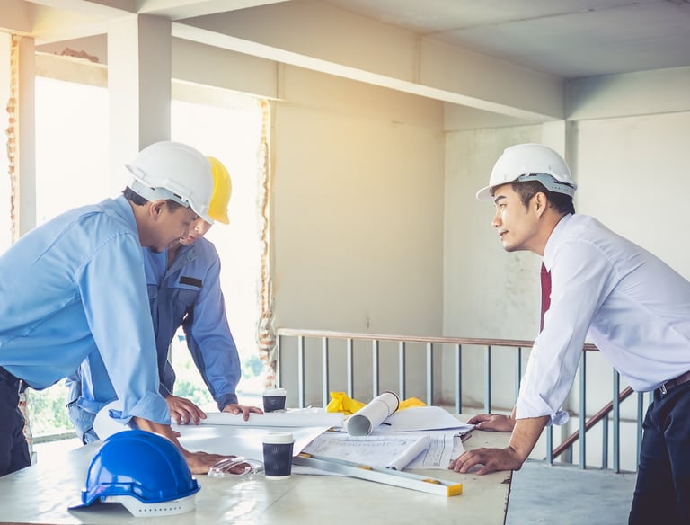 two men in hard hats and hard hats are standing in front of a table