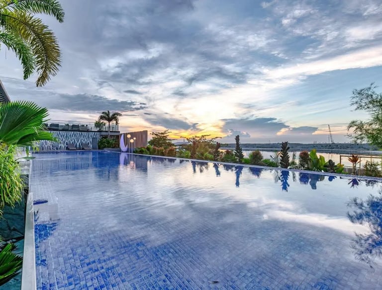 a pool with a view of the ocean and a sunset