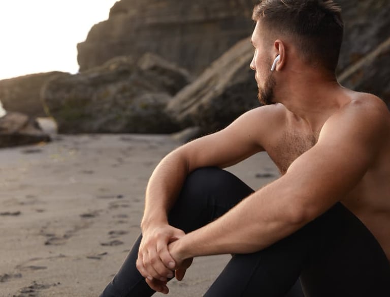 a sugar baby sitting on a beach with a cell phone in his hand