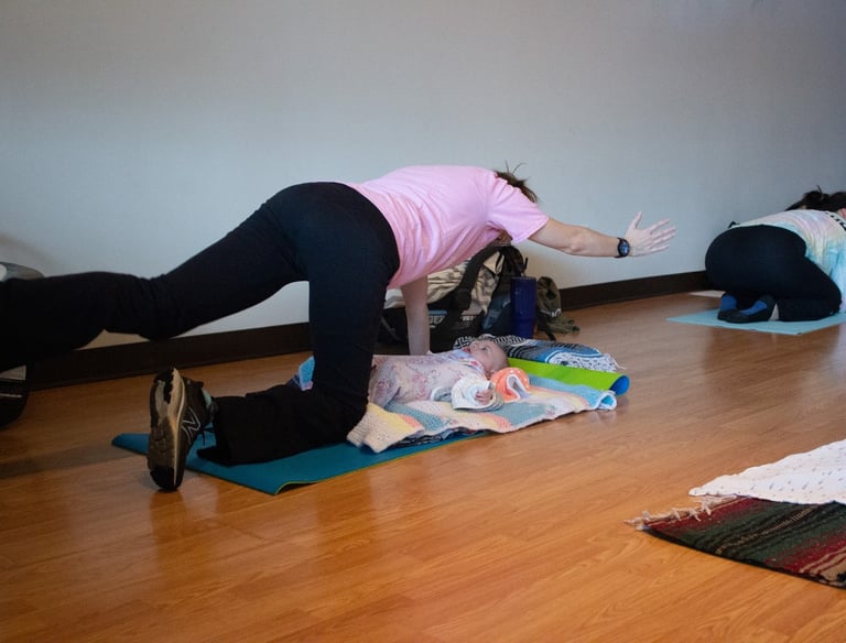 Mother in Spinal Balance yoga pose with Infant under her.