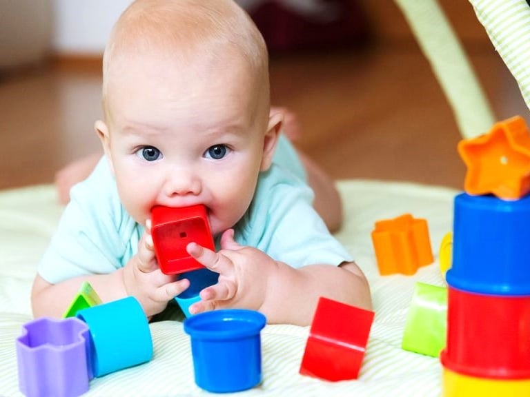 Un bebe mordiendo una pieza de plastico hecha de pigmentos de alta seguridad, libre de metales.