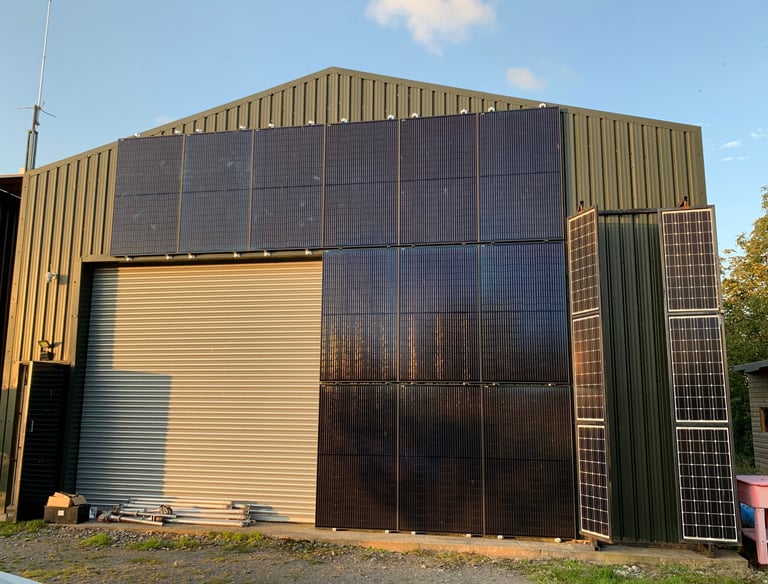 a building with vertical solar panels mounted in black on agricultural building