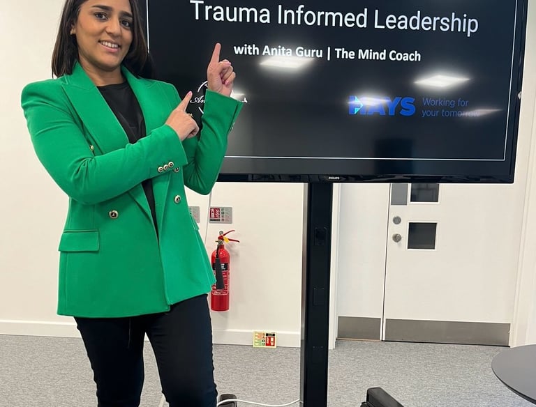 A photo of Anita standing in front of a large screen with a presentation on.