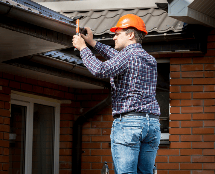 Ein Mann was eine Dachrinne repariert