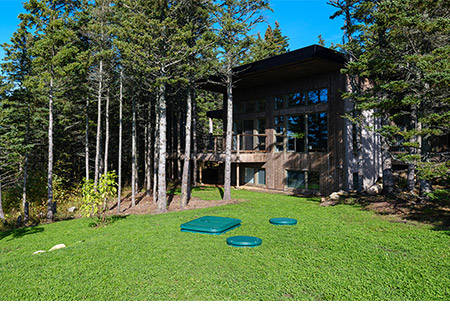 home with dome lids showing of a sanitary sewer aerobic package system with green grass and trees
