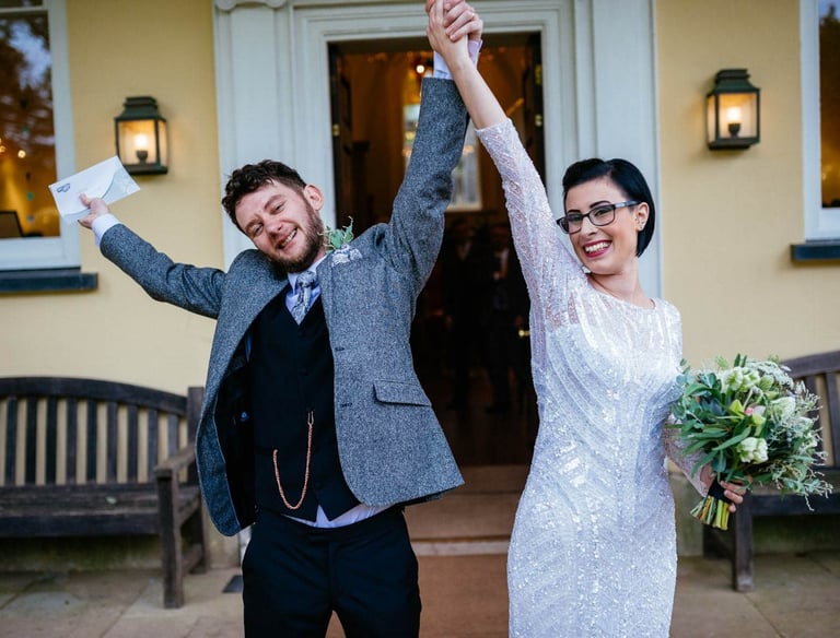 Just married joy at Aberglasney, bride and groom raising their hands in celebration outside the historic Welsh venue.