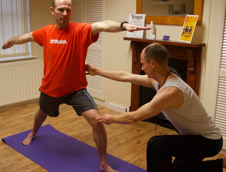 a man being corrected in a yoga pose by a yoga teacher